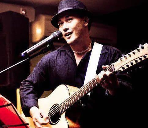 Performer singing and playing an acoustic guitar.